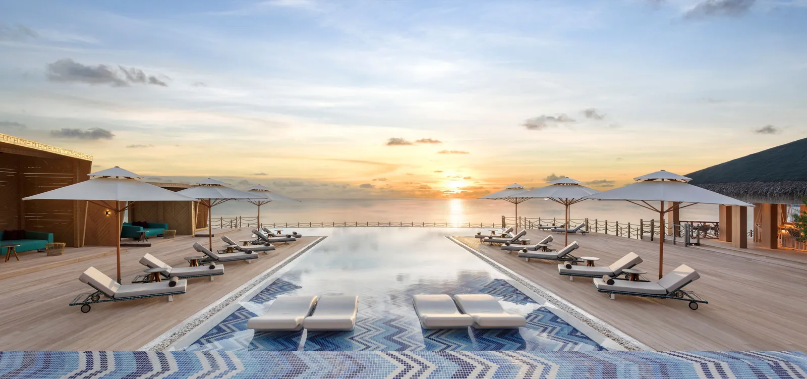 Horizon Pool at sunset, loungers and parasols along its edge facing the sea