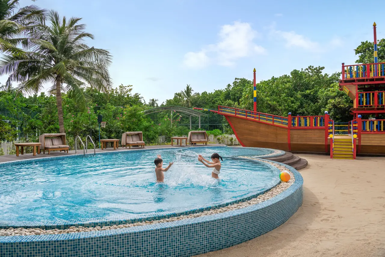 2 children in the kids’ club’s round pool, the pirate ship behind