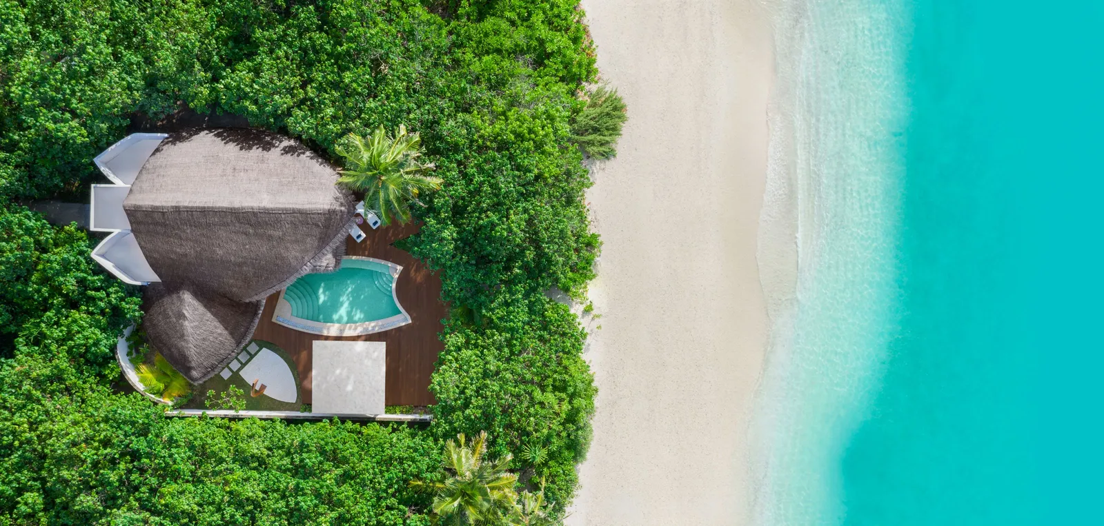 A beach villa from above, its pool among the trees and the white sand beside it