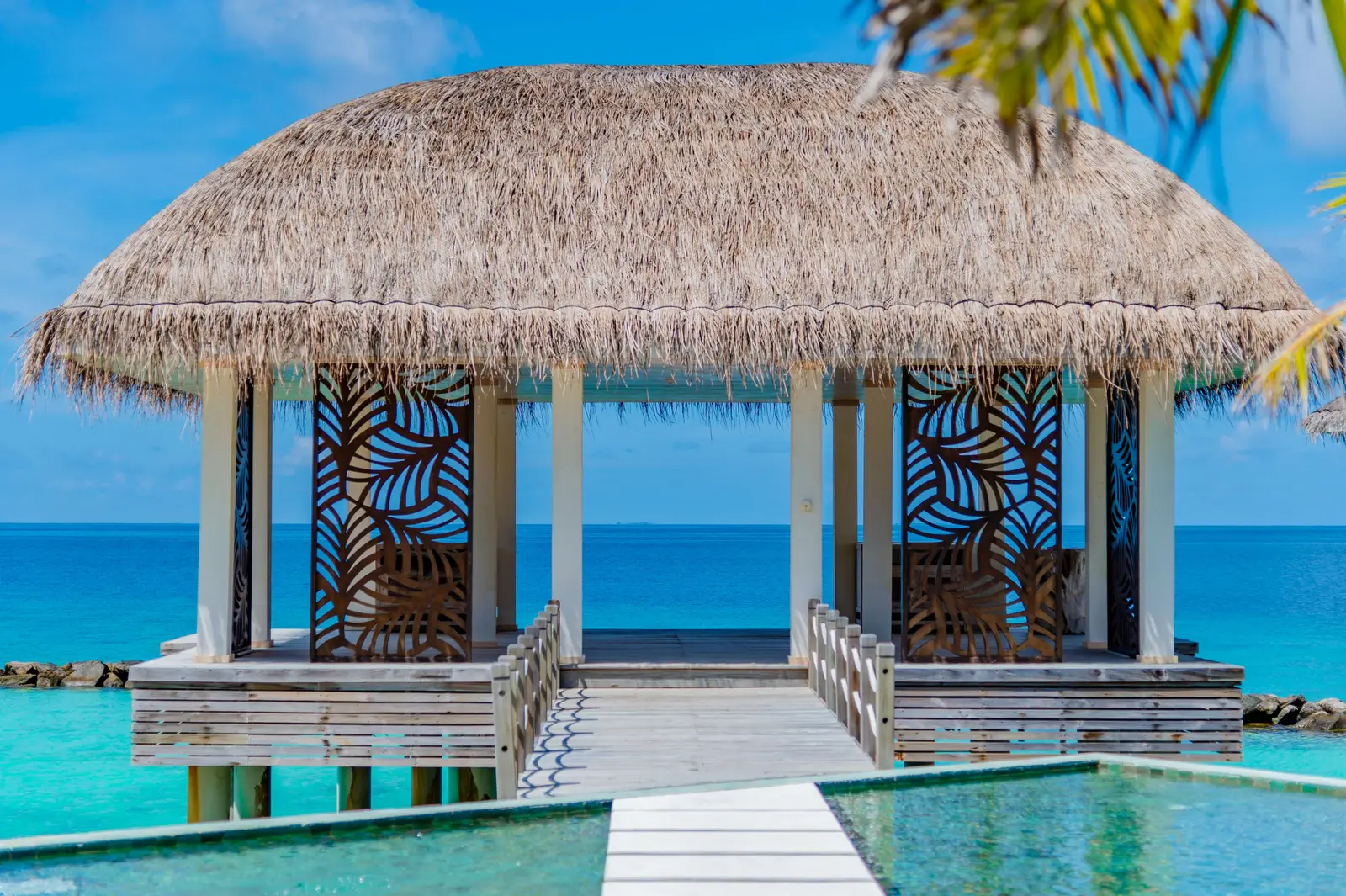The overwater yoga pavilion, its thatched roof and the lagoon around it