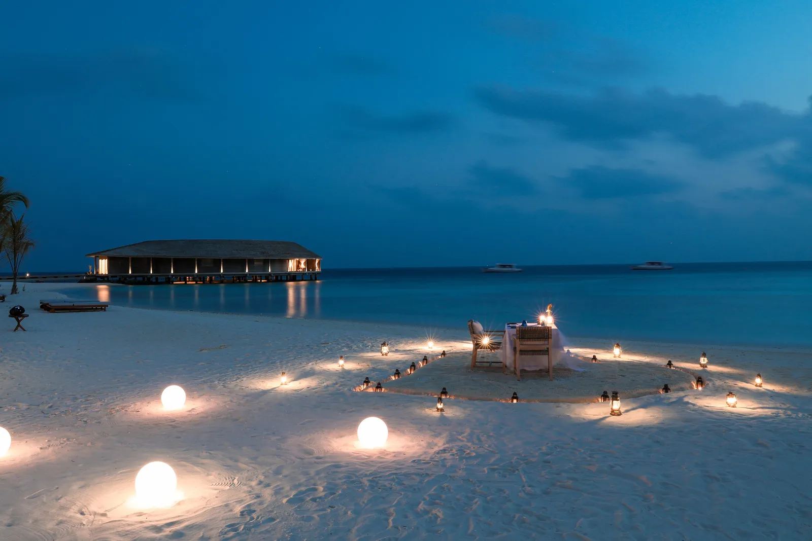 Dinner on the beach at night, the table in a ring of lights on the sand