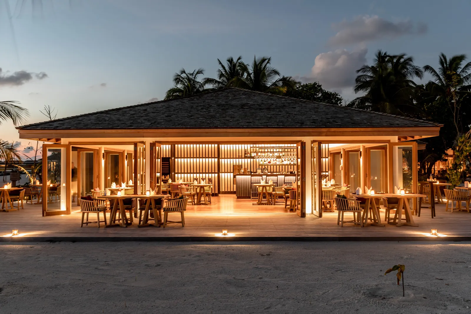Noo Faru lit at night, under its great open roof by the beach