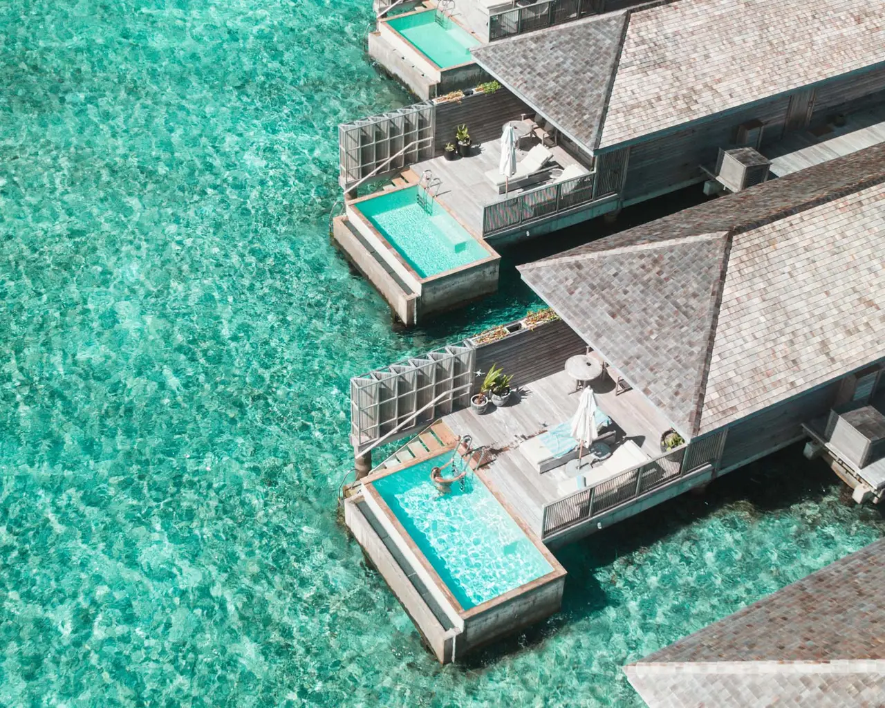 2 overwater villas from above, each with its pool on the deck