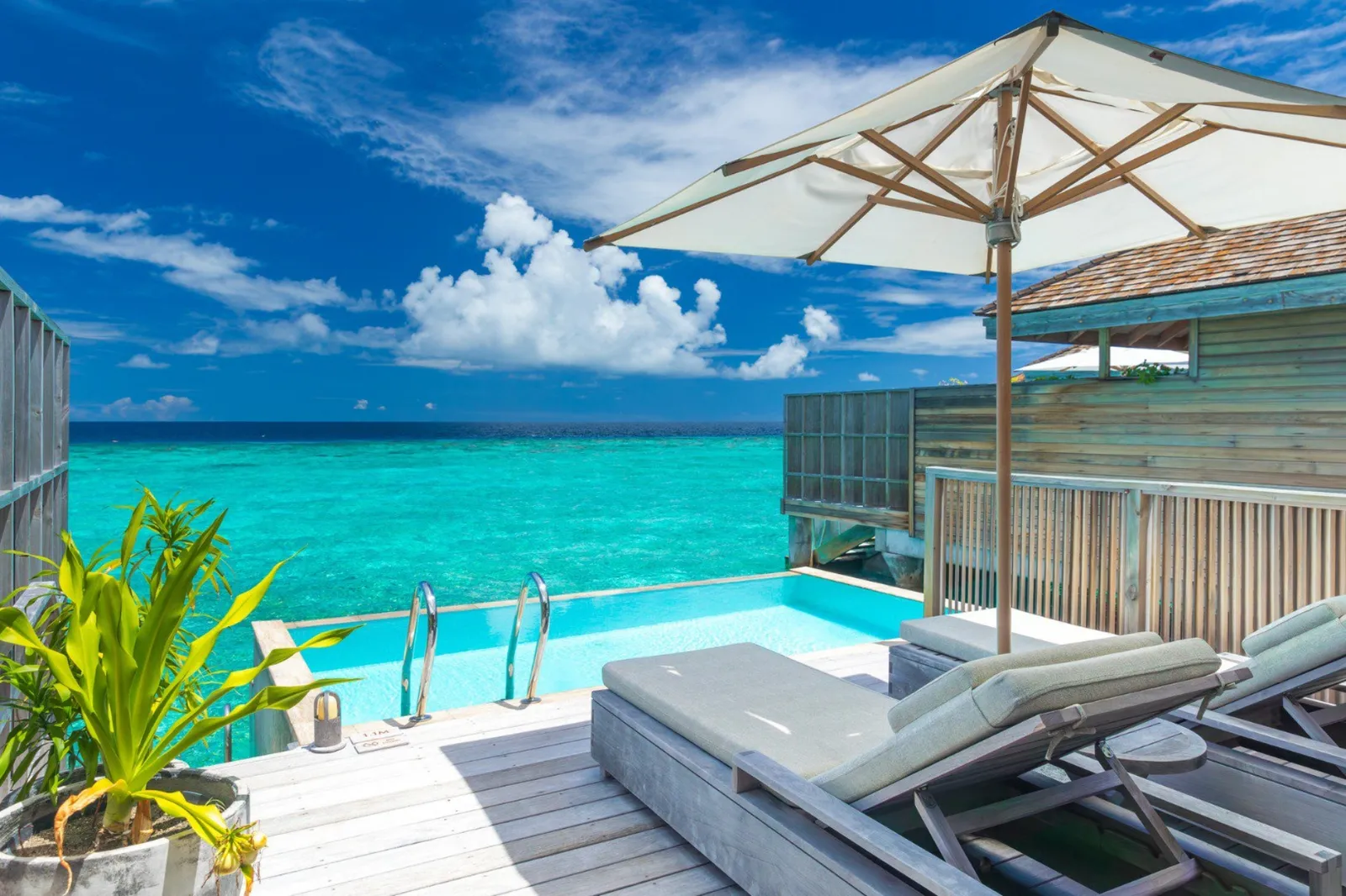 The pool on an overwater villa’s deck, loungers and the sea