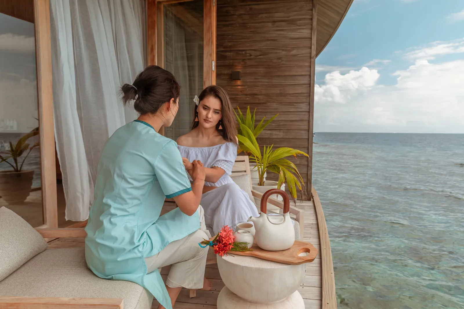 A Baani Spa therapist with a guest, on the deck facing the sea