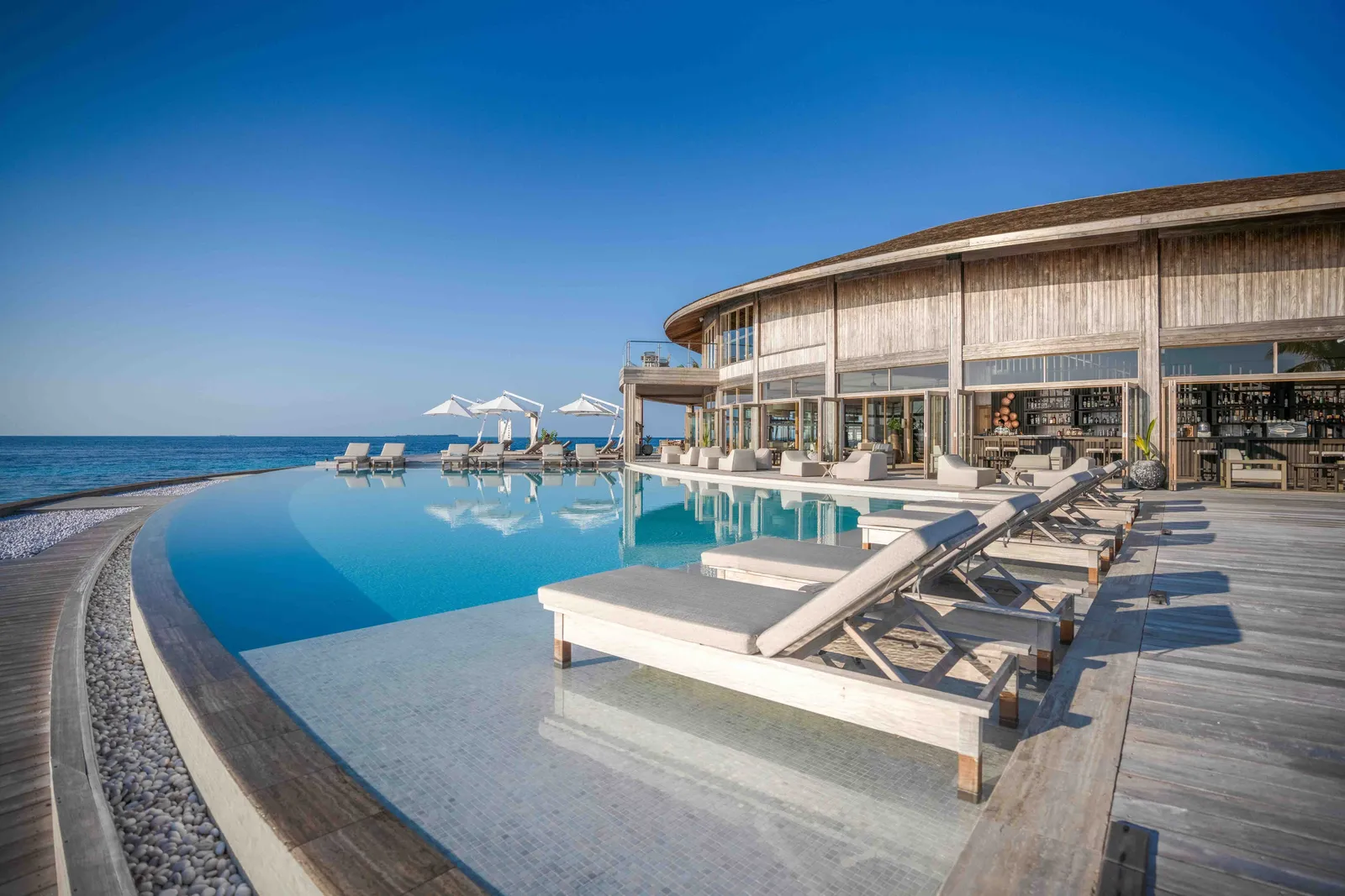 Ufaa’s infinity pool above the sea, loungers and the bar behind