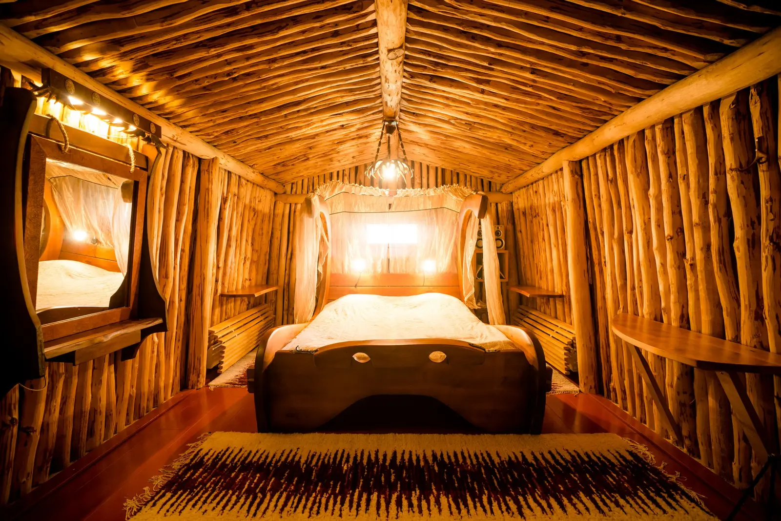 The Wedding Chamber: a long room lined with wooden branches, the bed at the far end under a warm light.