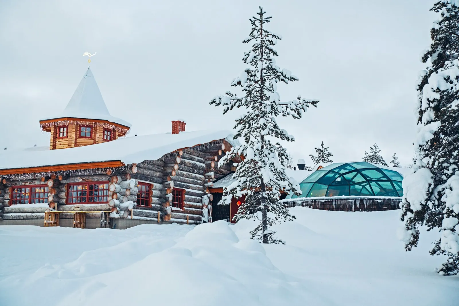 The log building of the Aurora Restaurant under snow, with its pointed turret and, beside it, the glass dome of the Igloo Bar.