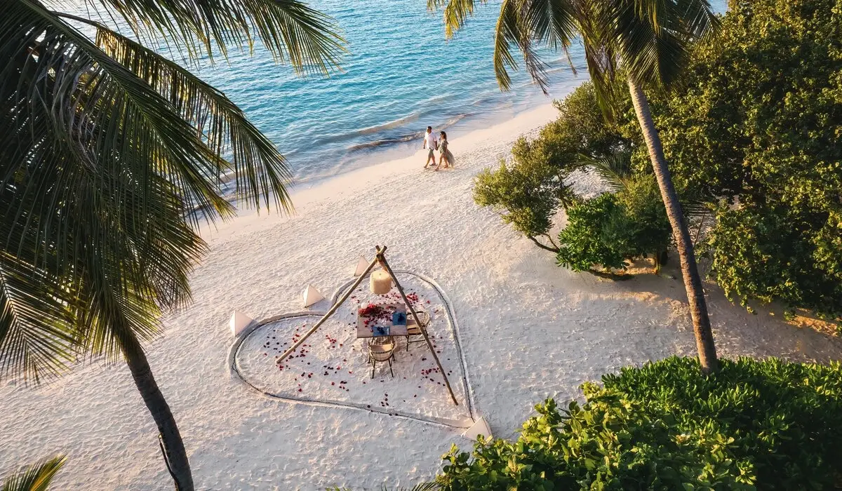 A picnic on the sand from above, inside a heart drawn on the beach