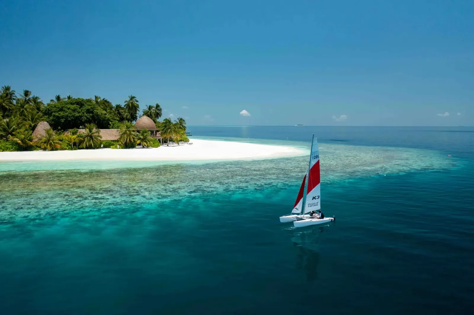 A sailing catamaran off Kandolhu’s white beach