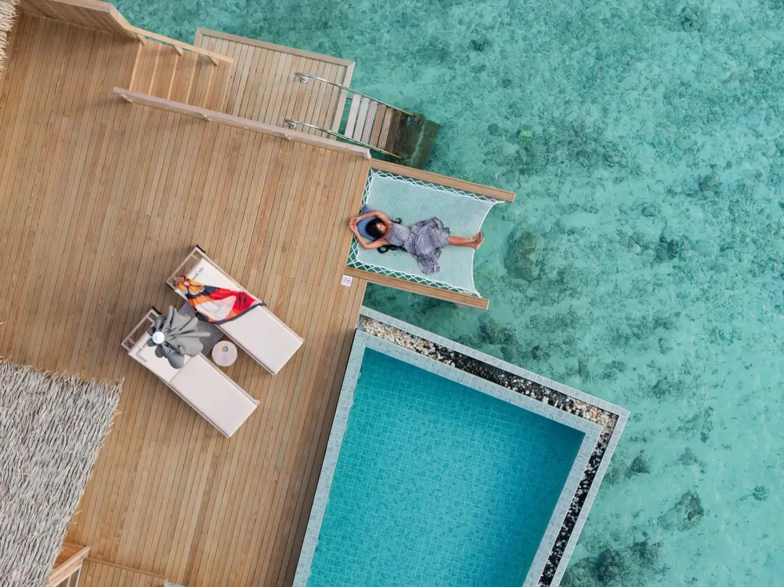 A water villa’s deck from above: the pool, the loungers and the lagoon