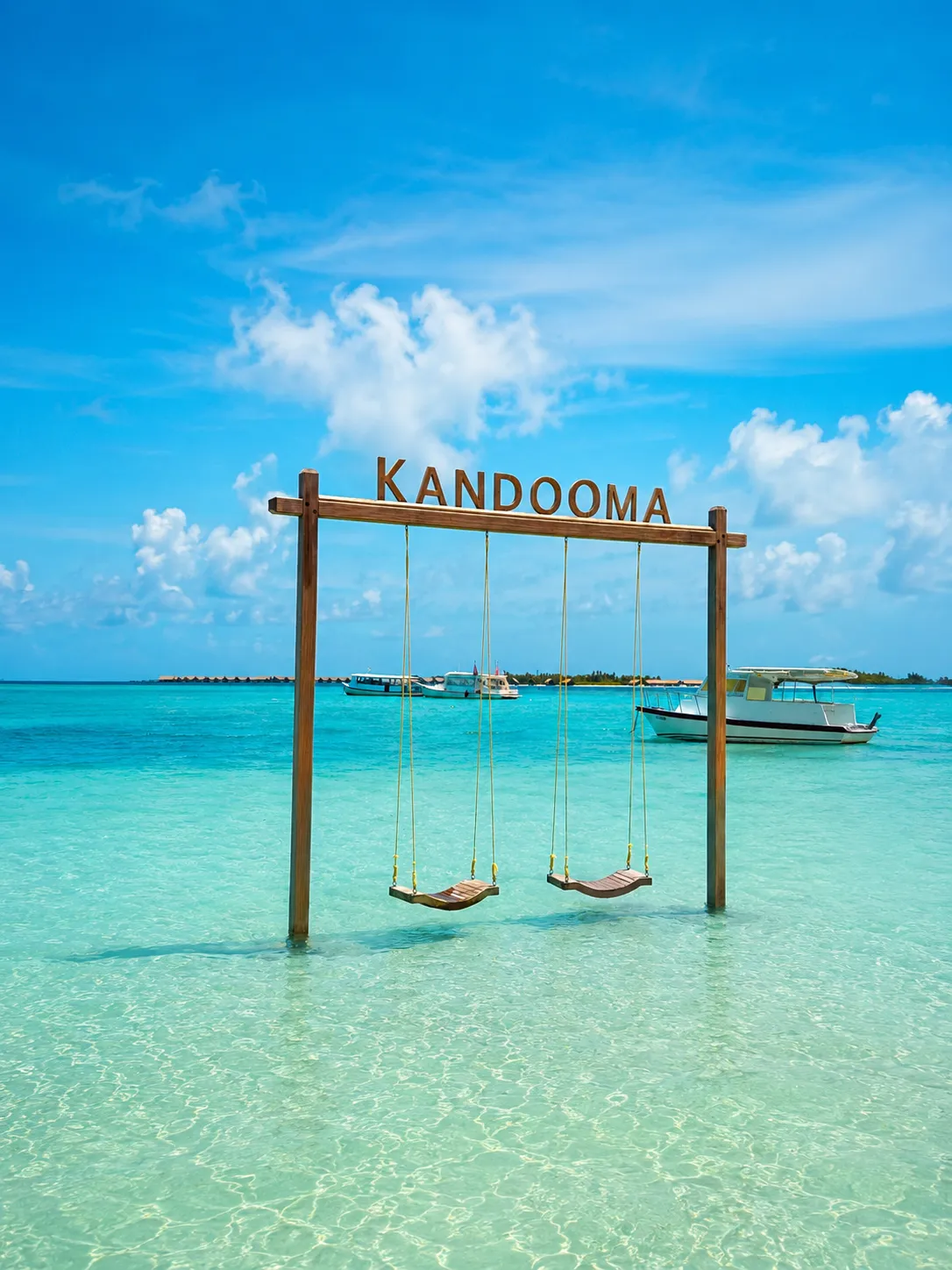 The swings under the Kandooma sign, set in the shallow lagoon.