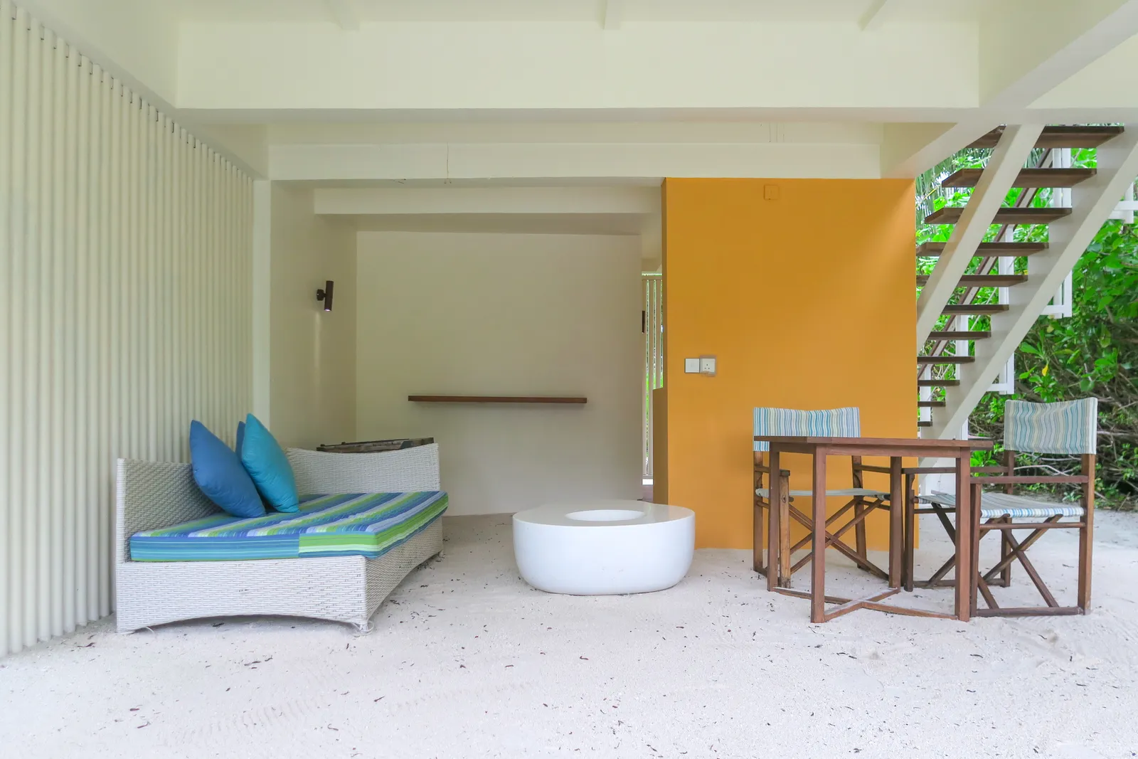 The ground floor of a Beach House: the sofa, the table and the wooden stairs up to the bedroom.