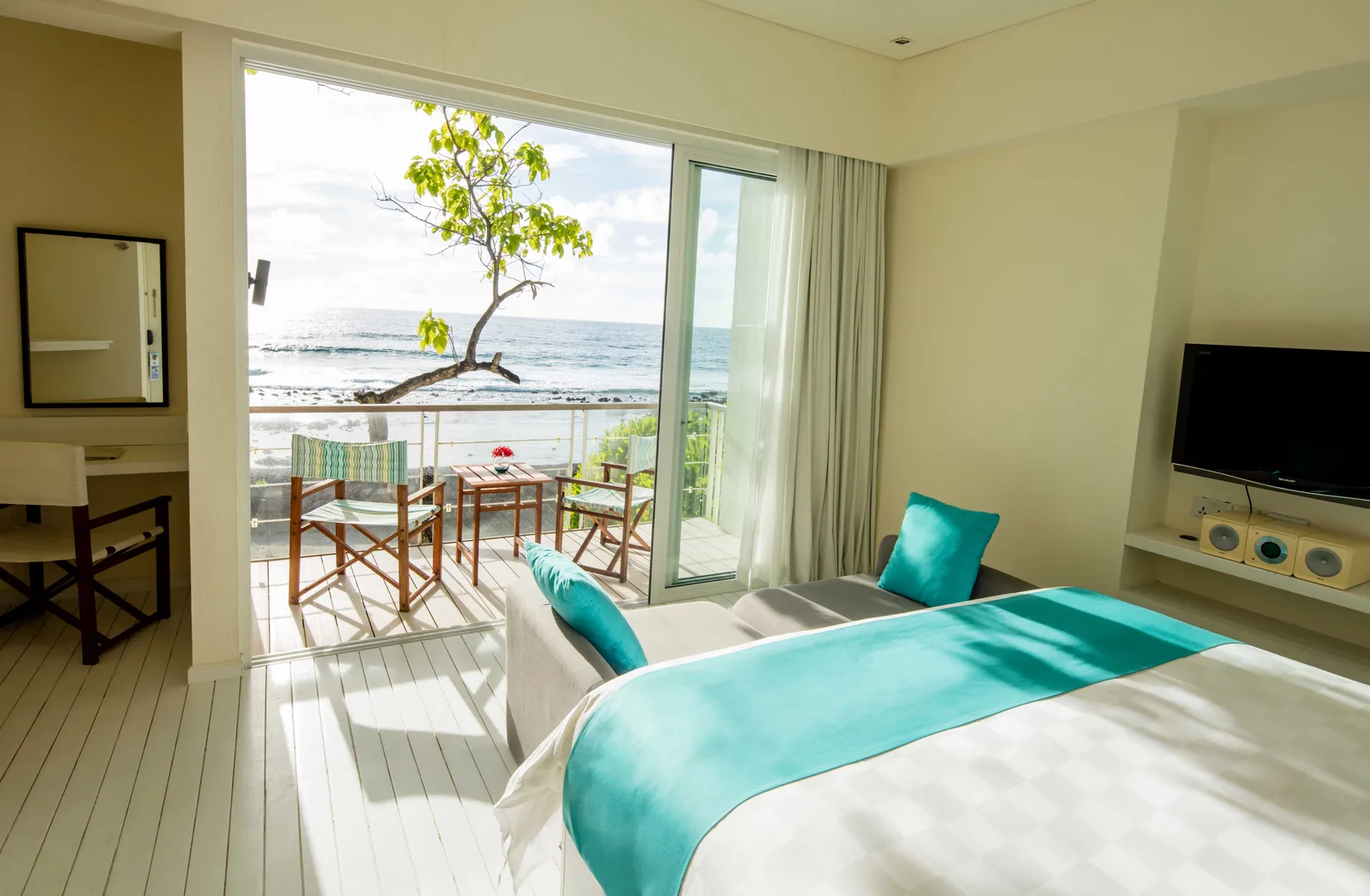 The upstairs bedroom of a sea-view Beach House, with the bed and the open balcony.