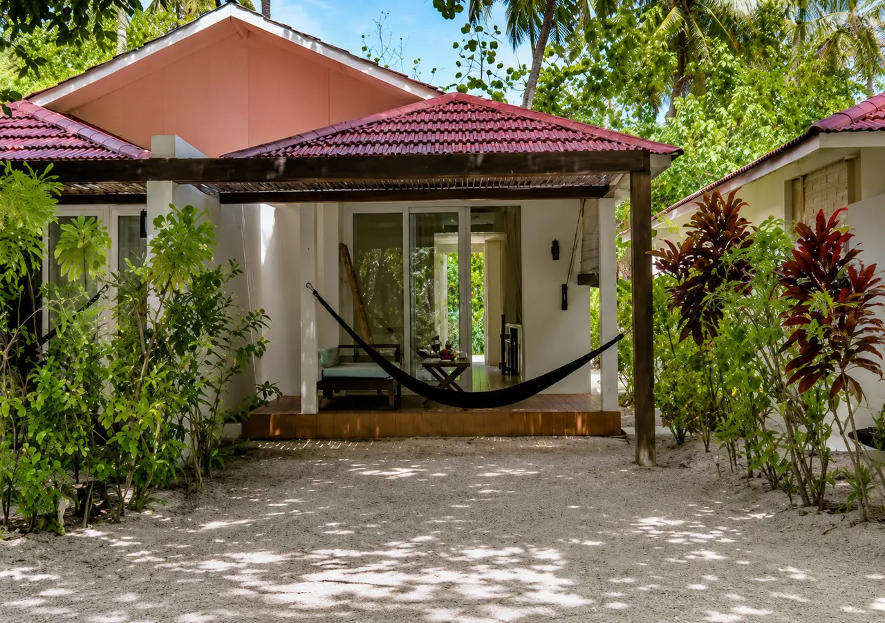 A Garden Villa among the plants: the red roof, the hammock under the veranda and the sand in front.
