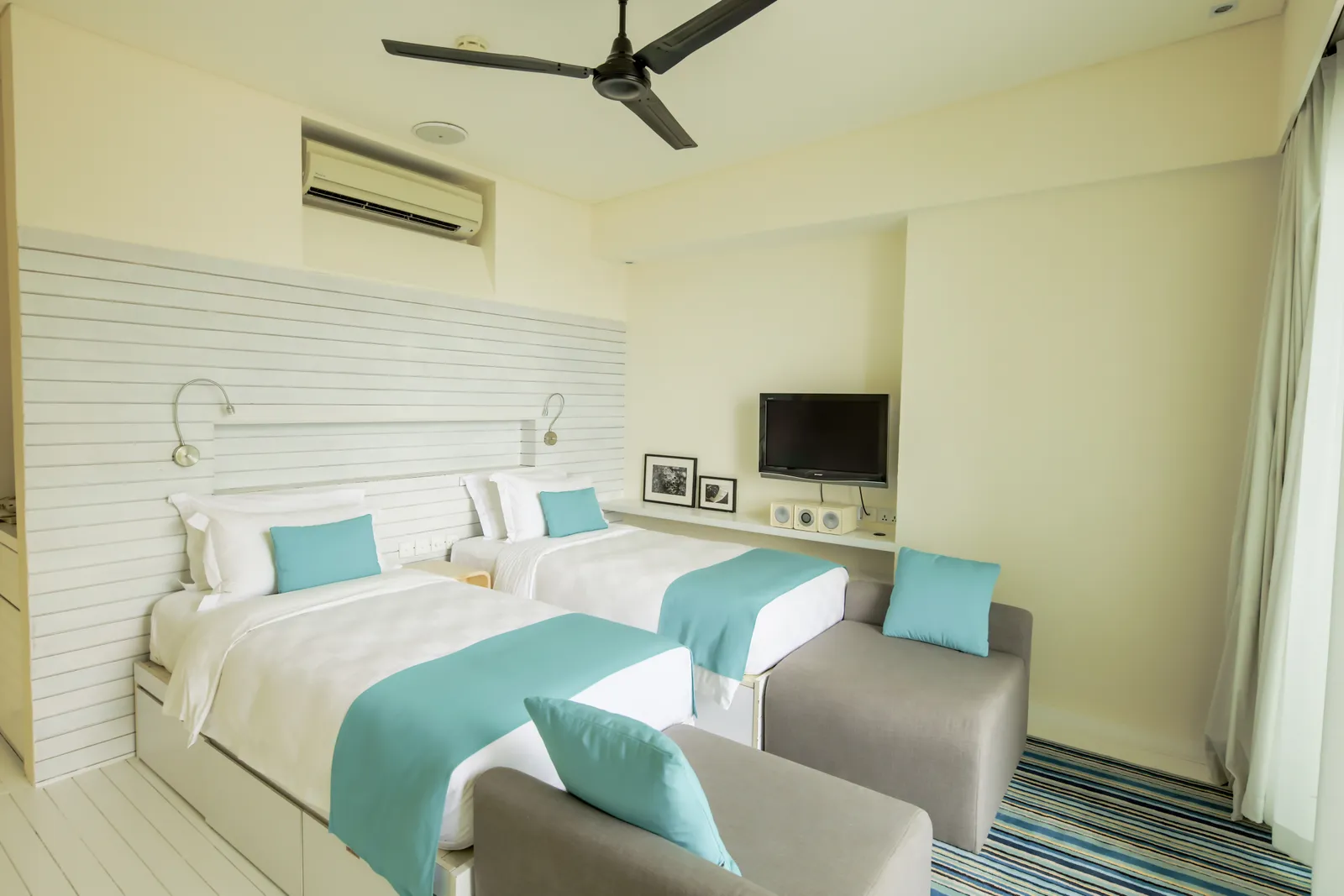 The twin bedroom of a family Beach House, with the ceiling fan and the TV.