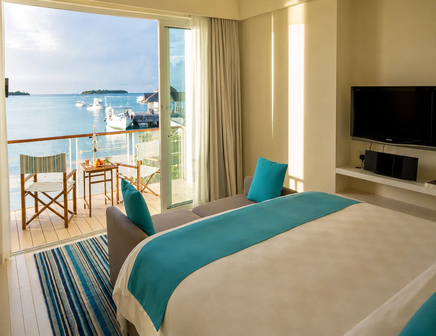 A bedroom of the 2-bedroom Beach House: the bed and the door open onto the balcony and the sea.