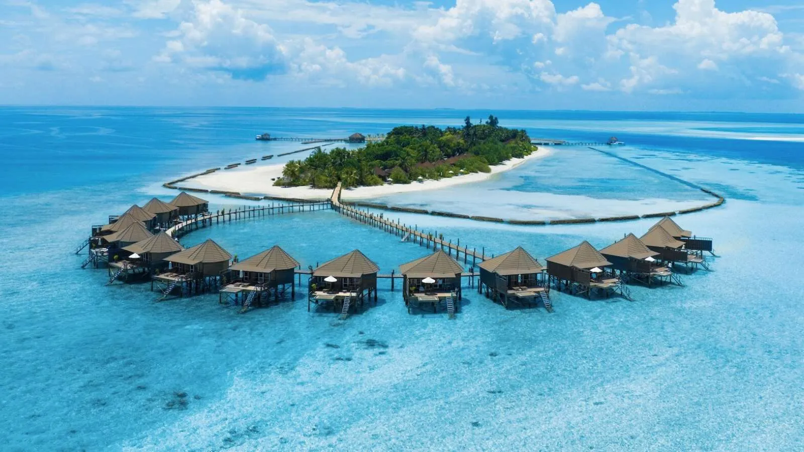 The crescent of water villas in front of the island, with the white spit of sand and the open sea.