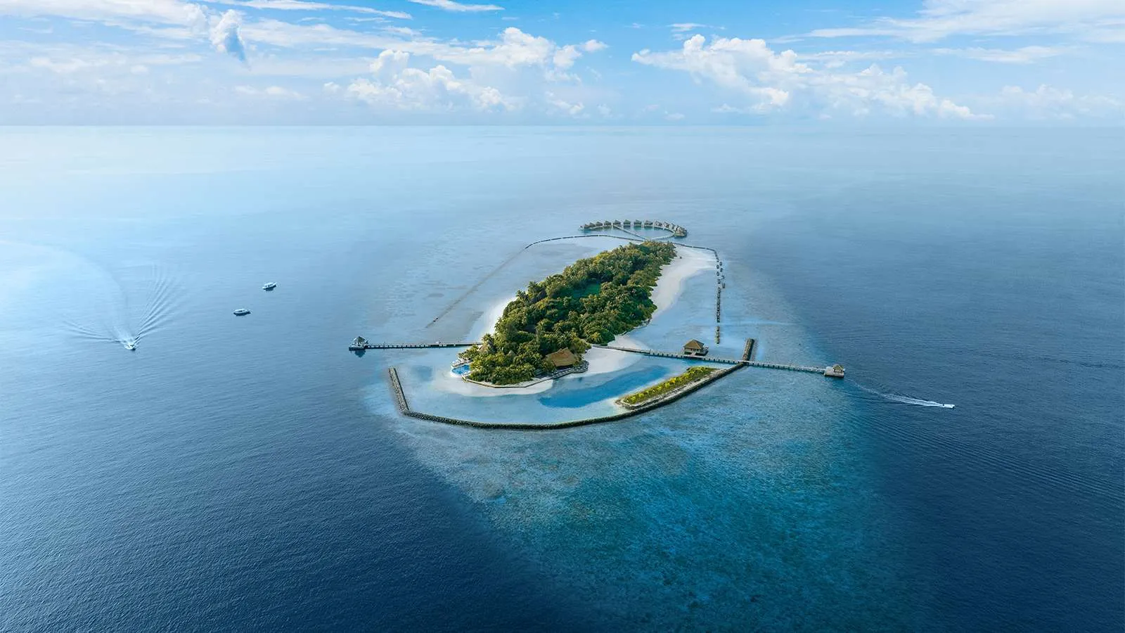 The island seen from afar, small and green in the middle of the atoll, ringed by its pale lagoon and the blue sea.