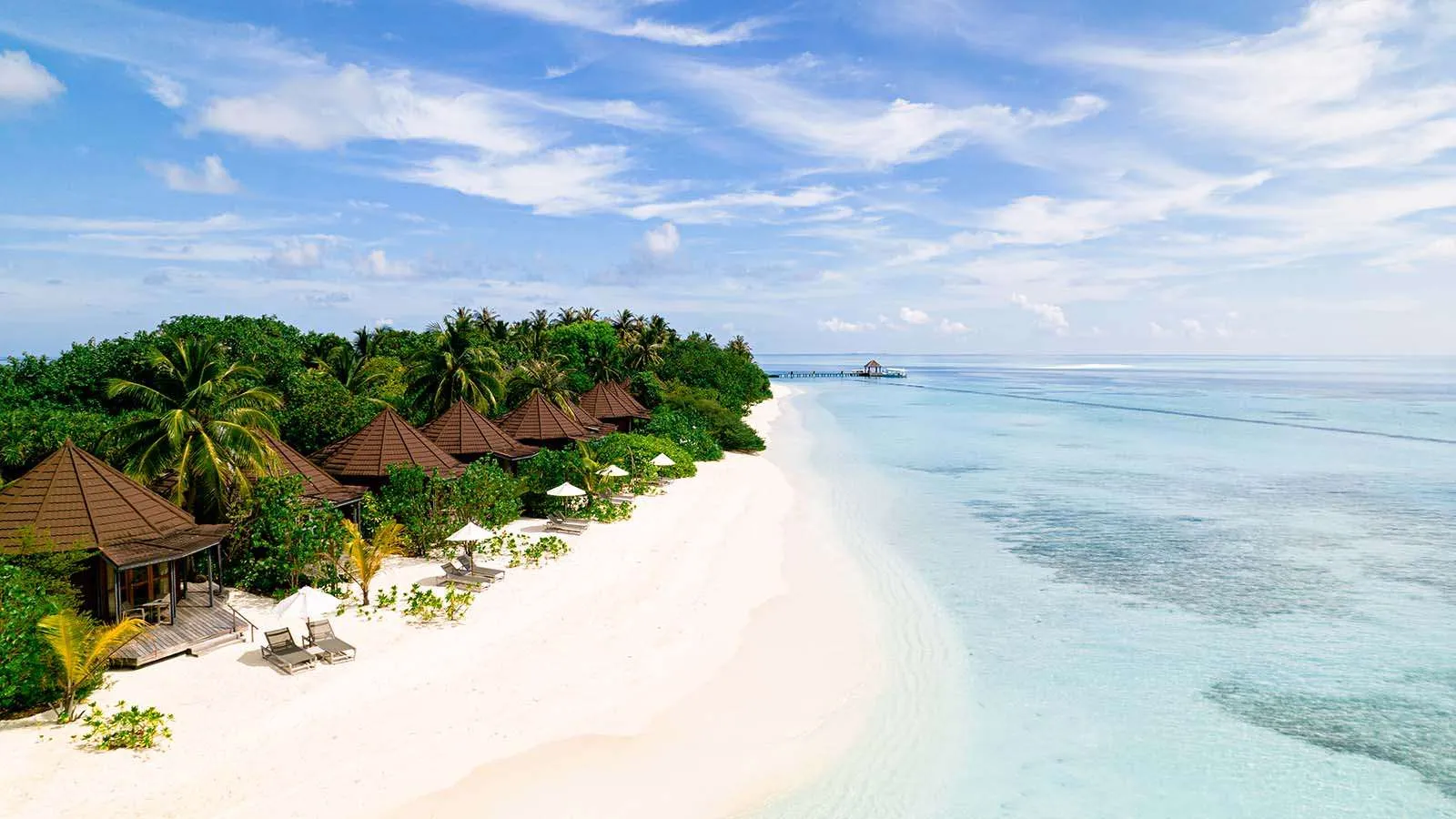 The beach villas from above, among the palms, along the white sand and the shallow lagoon on the sunrise side.