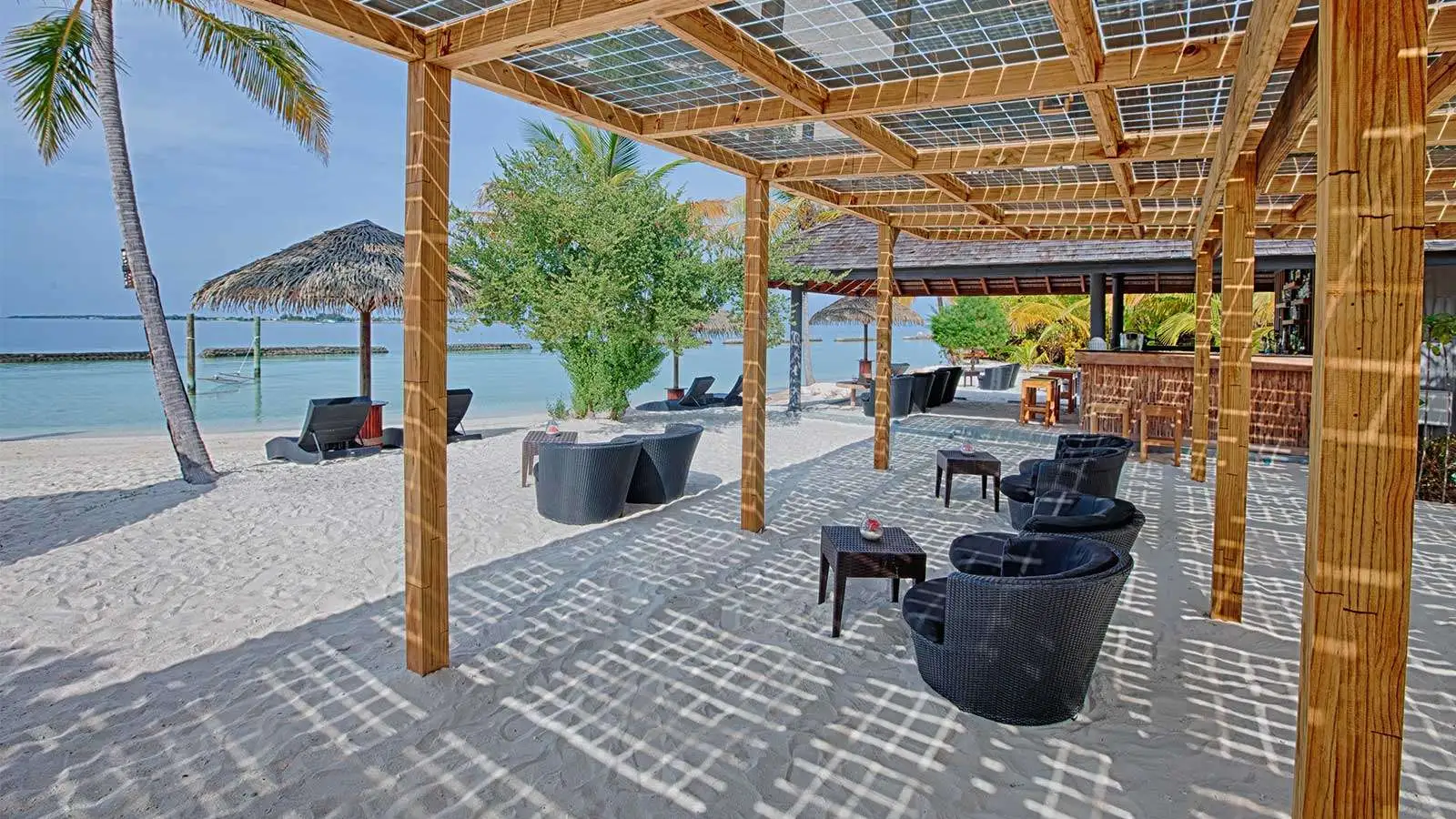 Thundi Bar on the beach, under the pergola with its solar panels, armchairs on the sand and the sea behind.