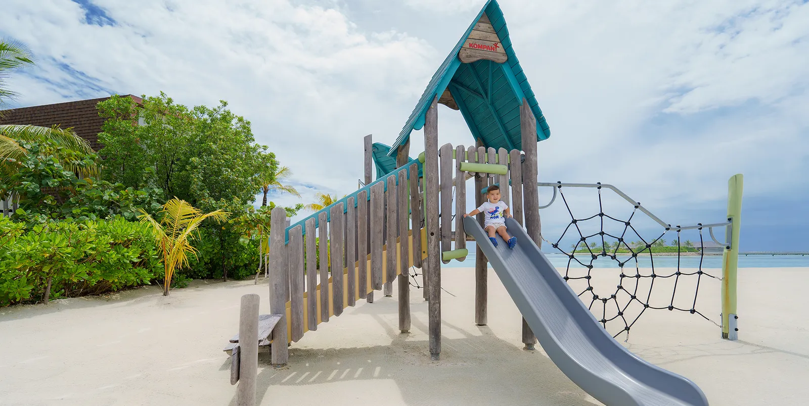 Kuda Fiyo's outdoor playground on the sand: the timber tower, the slide and the climbing net.