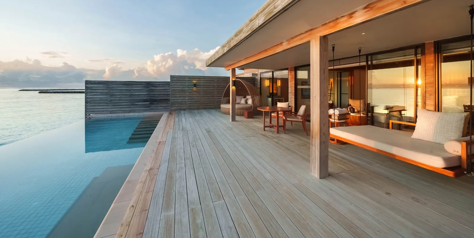 A Sunrise Water Villa's deck, with the sofa under the roof and the infinity pool over the lagoon.