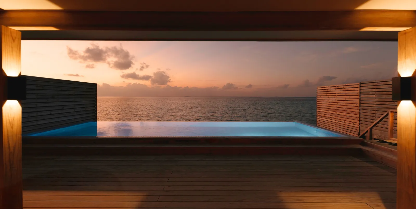 A Sunset Water Villa's pool at sunset, between 2 timber screens, facing the open sea.