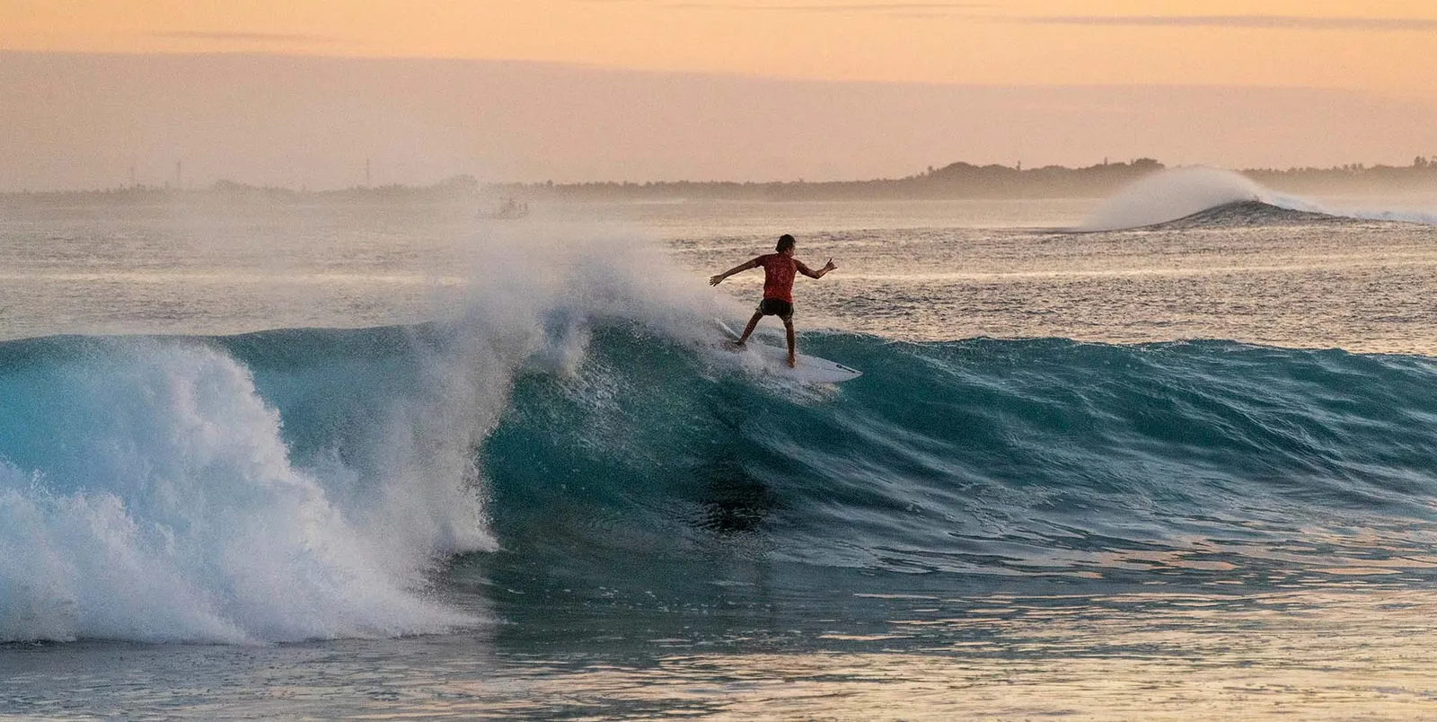 A surfer riding the left-hander at Chickens, the break off the island, at dawn.