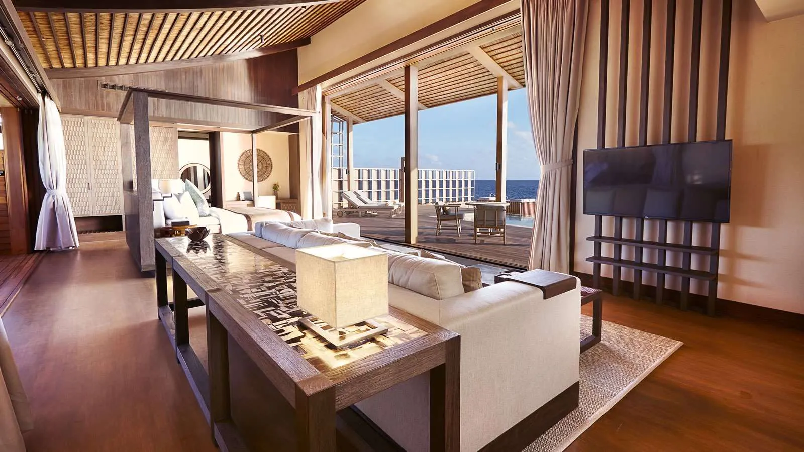 Inside a residence: the living area, the bed and the glass walls onto the sea