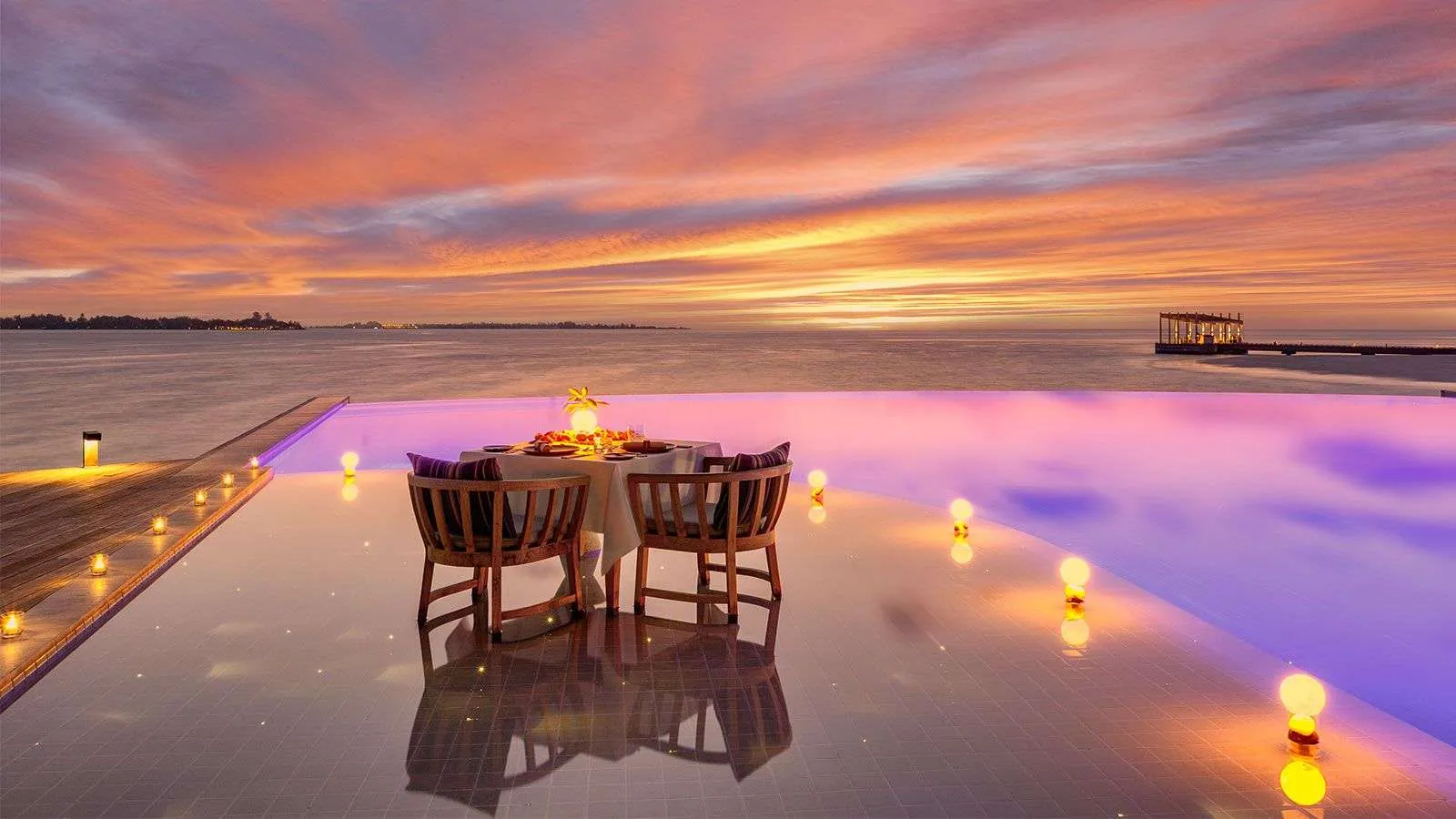 A table for 2 on the edge of the Retreat pool at sunset, candles reflected in the water