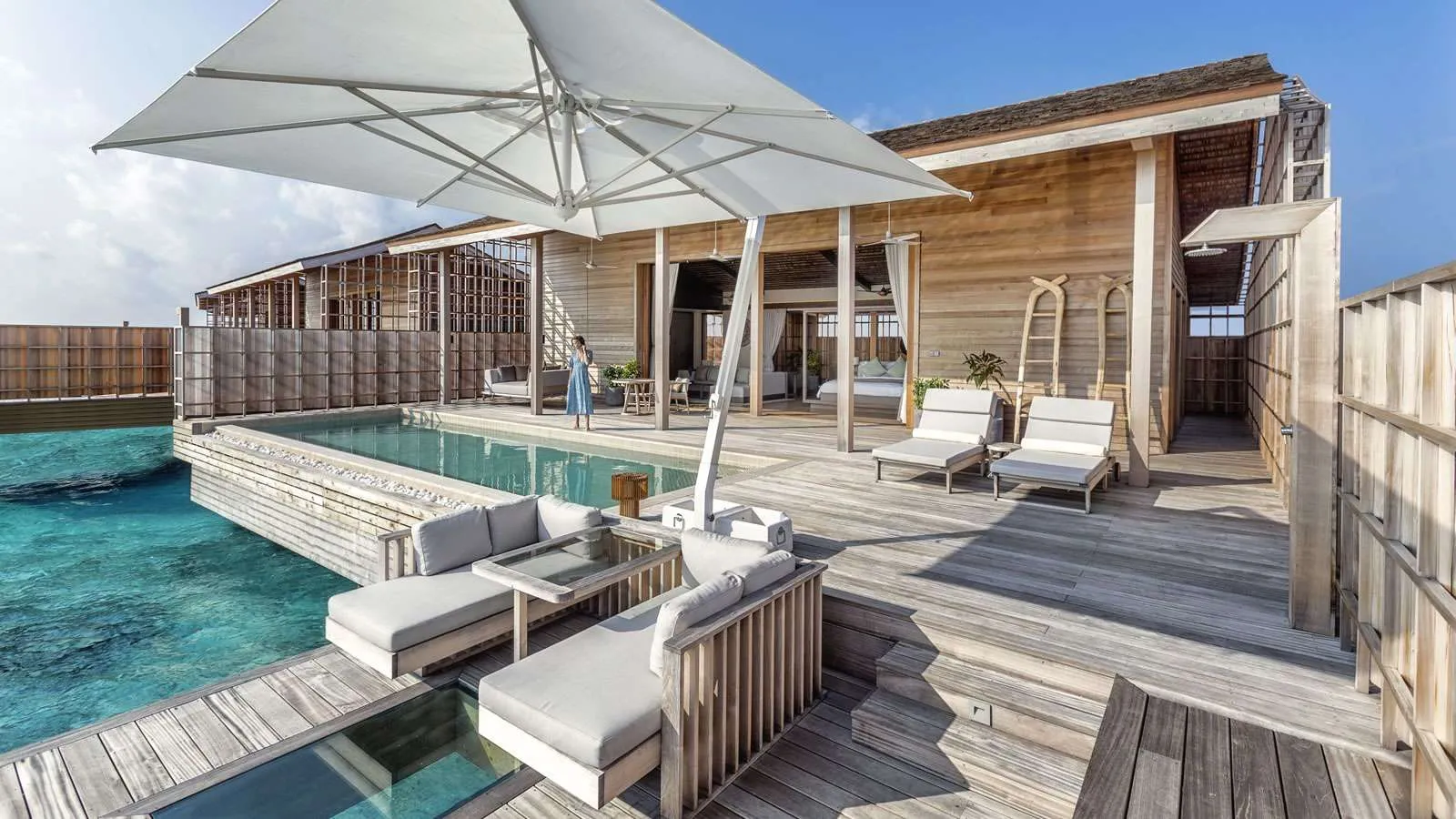 A residence deck: the parasol, the loungers and the infinity pool above the lagoon
