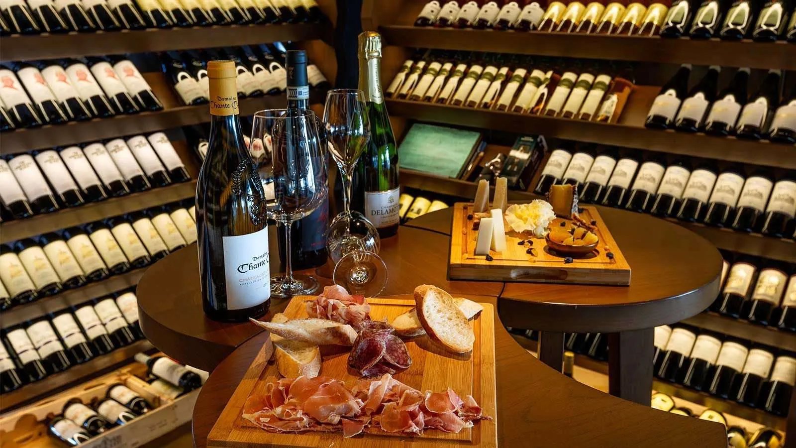 The wine cellar: bottles on the shelves and a table with glasses and charcuterie