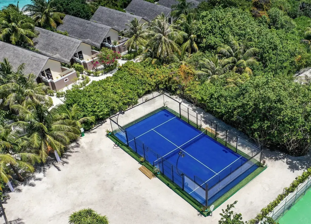 The padel court from above, among the palms and the roofs of the beach villas.