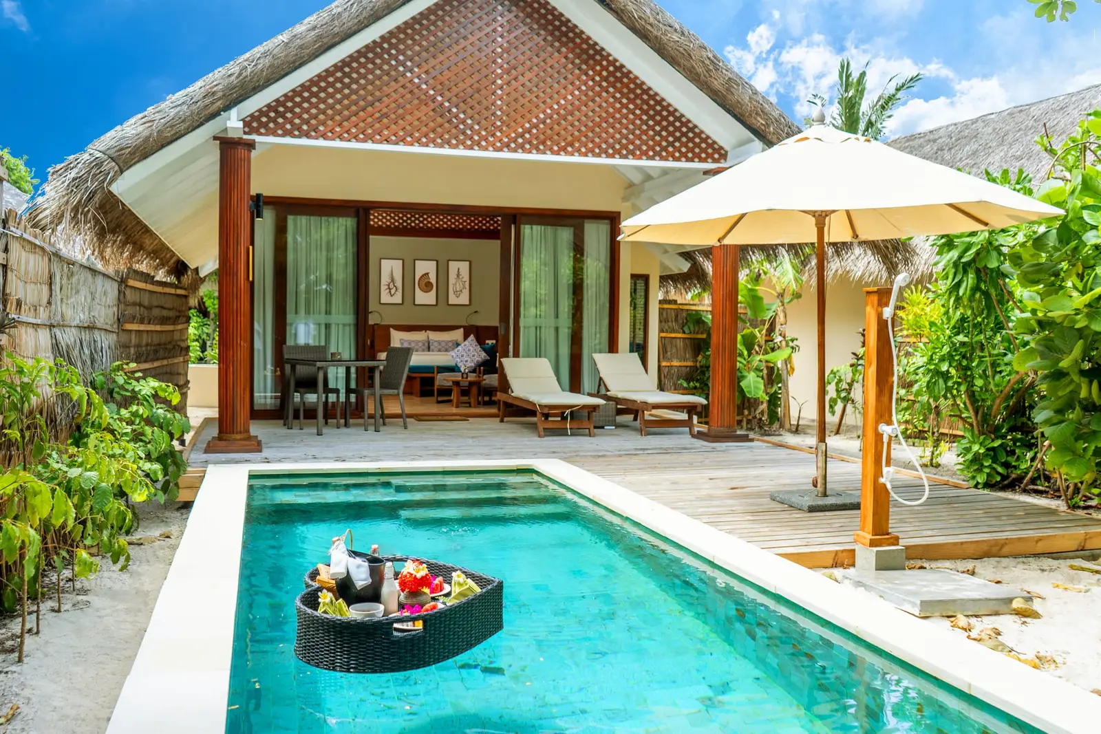 A Beach Villa with Pool’s private pool, with breakfast floating on it, loungers and a parasol in front of the villa.