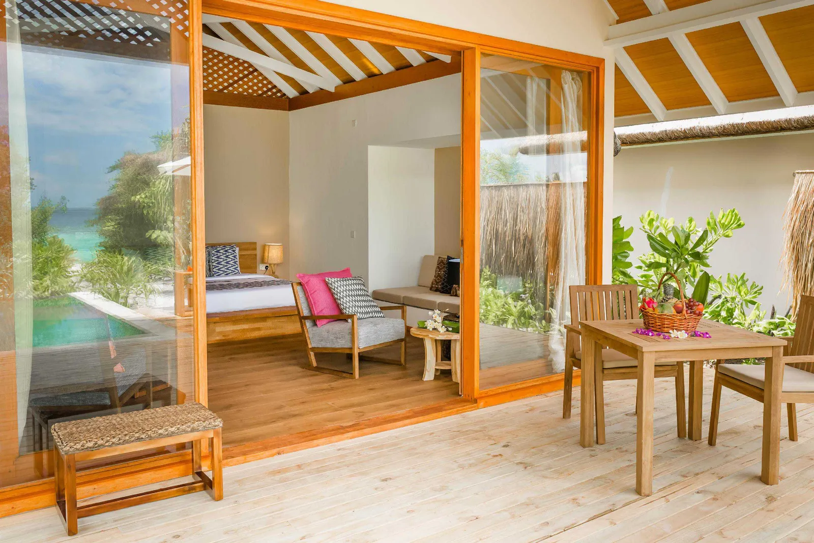 The Beach Villa from its terrace: the bedroom and sitting area beyond the sliding doors, the outdoor table and the garden.