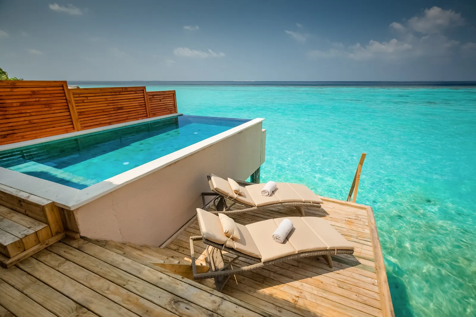 A Water Villa with Pool’s infinity pool above the lagoon, with 2 loungers on the deck.