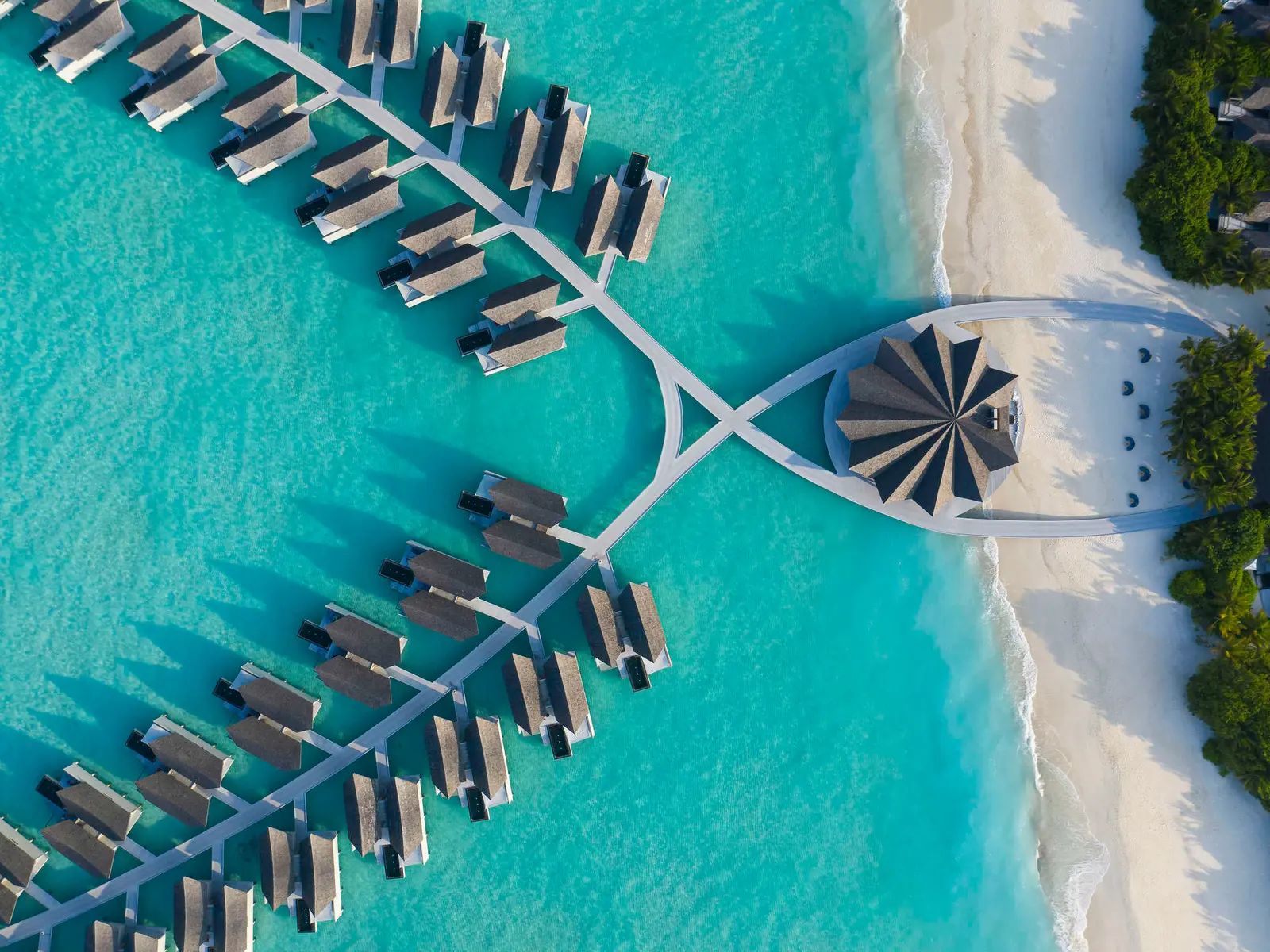 The overwater villa jetties from above, running from the beach into the lagoon