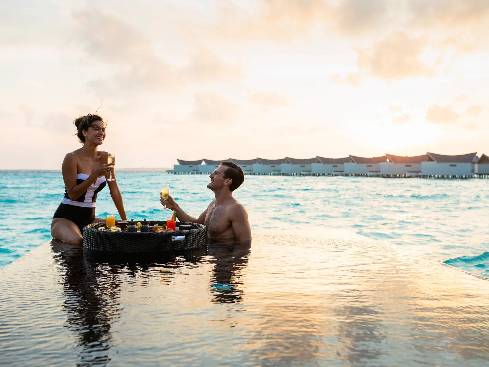 Breakfast on a floating tray in the lagoon, the overwater villas behind