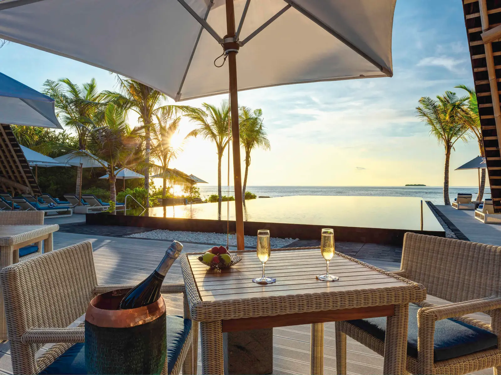 A table at Latitude 5.5 with champagne, the pool and the sea at sunset