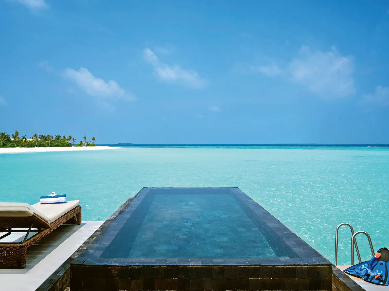 The infinity pool on an overwater villa’s deck, the sea beyond the edge