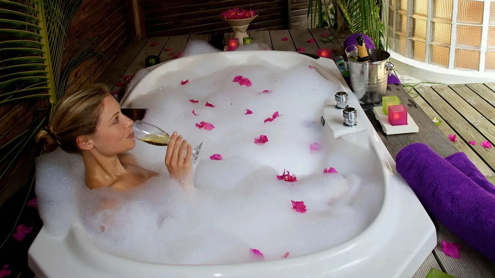 Jacuzzi Beach Villa bath with petals and a guest