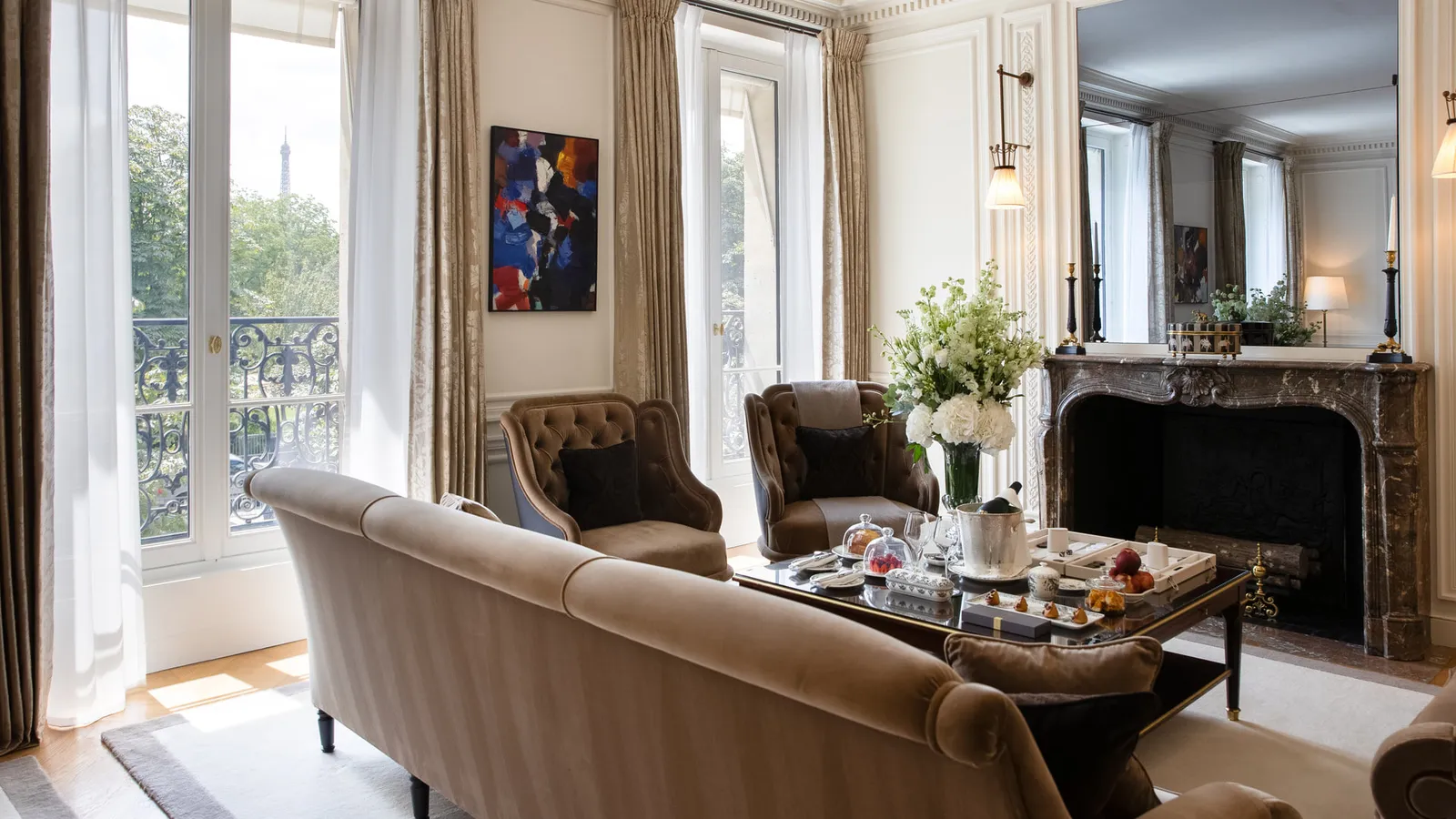 A sitting room with pale armchairs, a table and windows