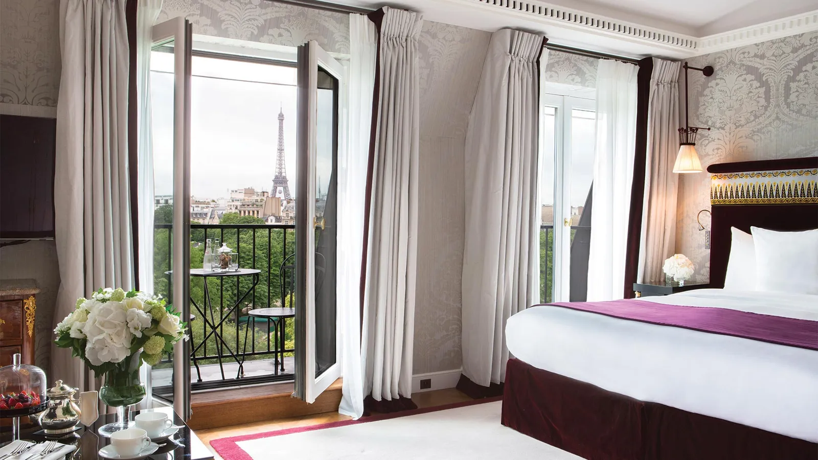 A bedroom with a bed and the Eiffel Tower beyond the window