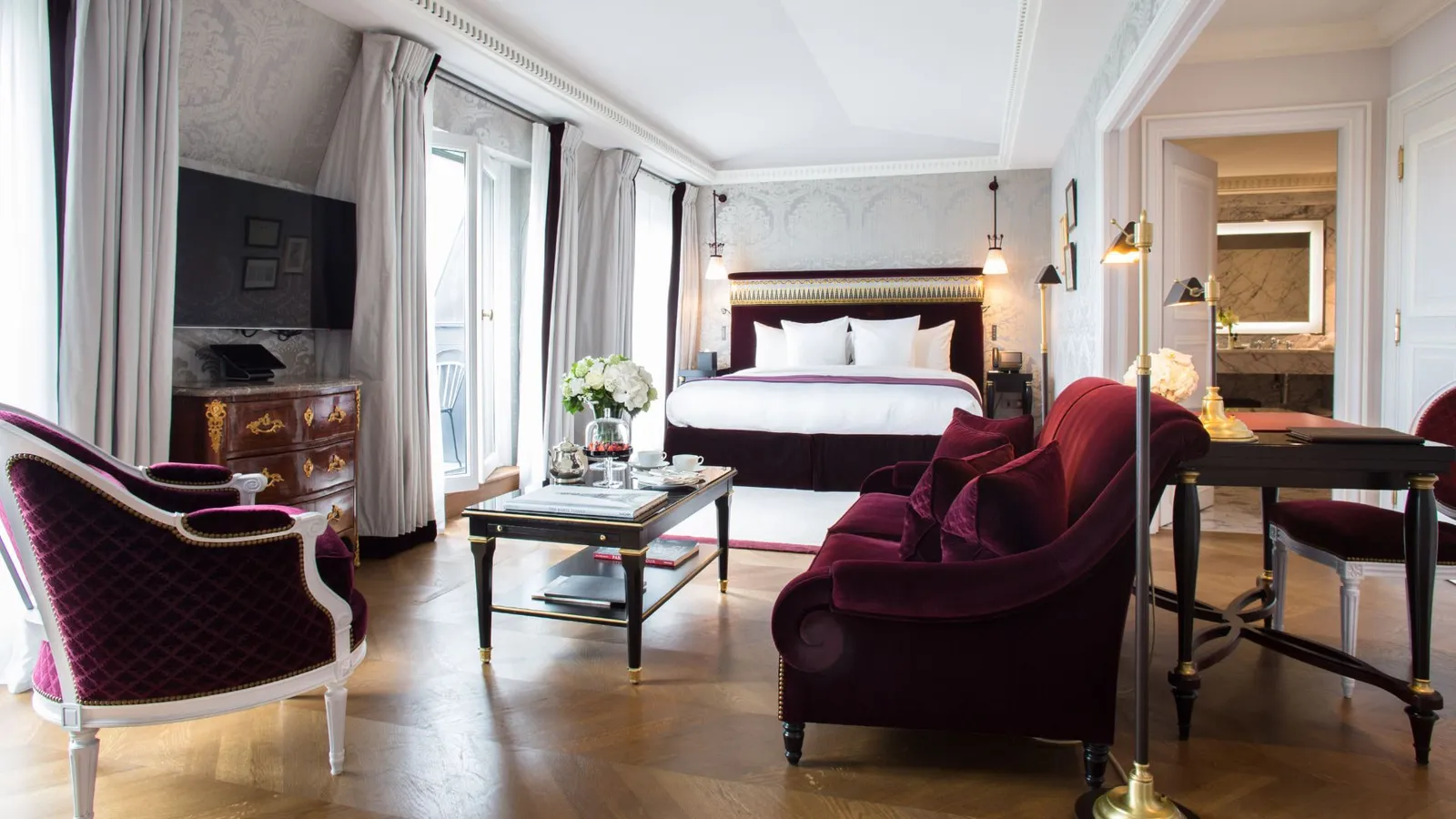 A bedroom with a bed, purple seating and a desk