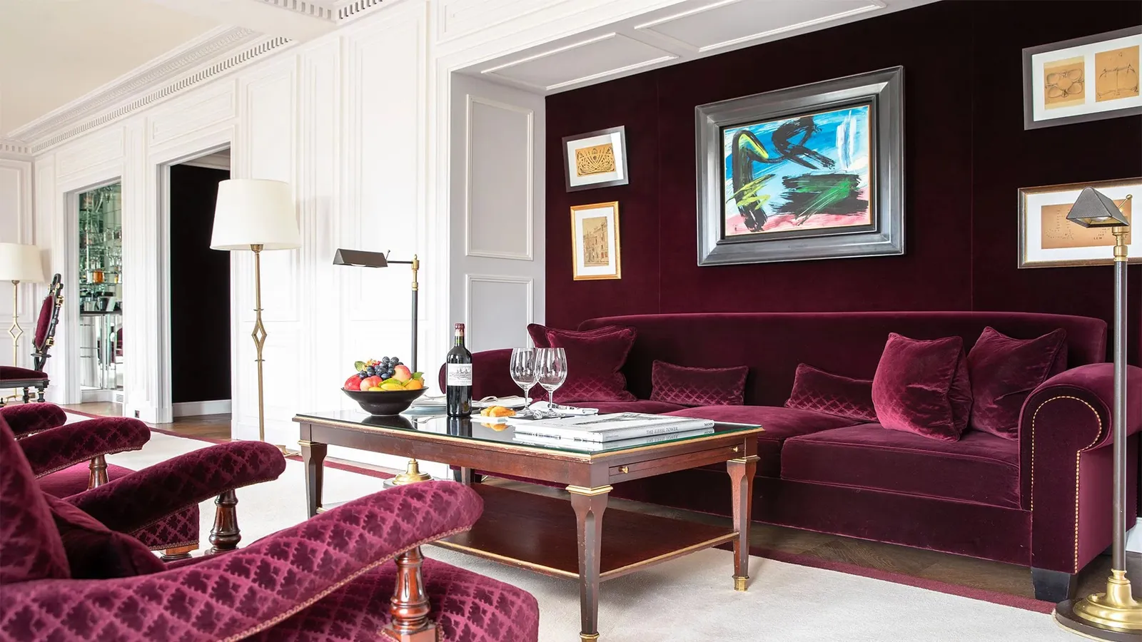 A sitting room with purple seating, tables and large windows