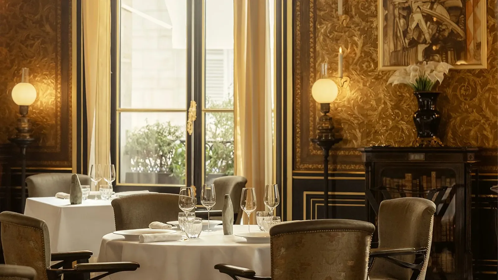 A dining room with laid tables, white tablecloths and windows