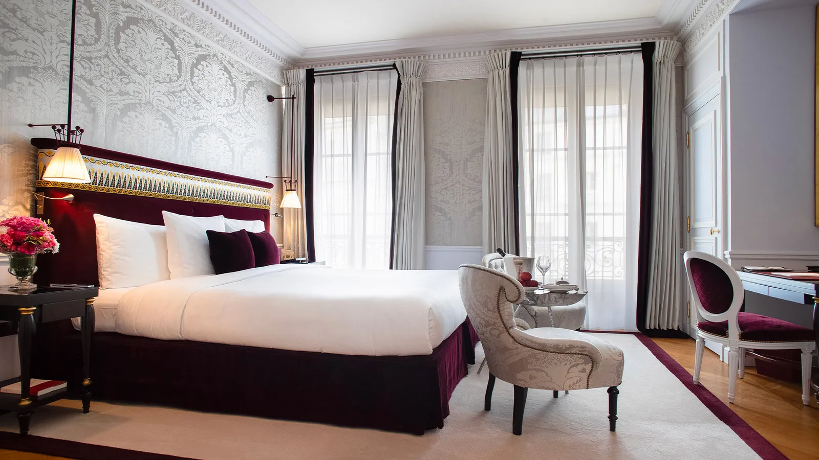 A pale bedroom with a bed and purple cushions