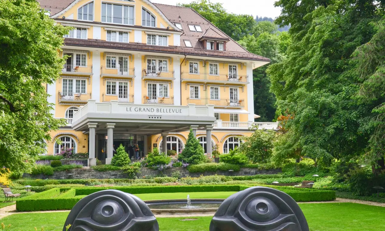 La facciata gialla del Grand Bellevue fra gli alberi