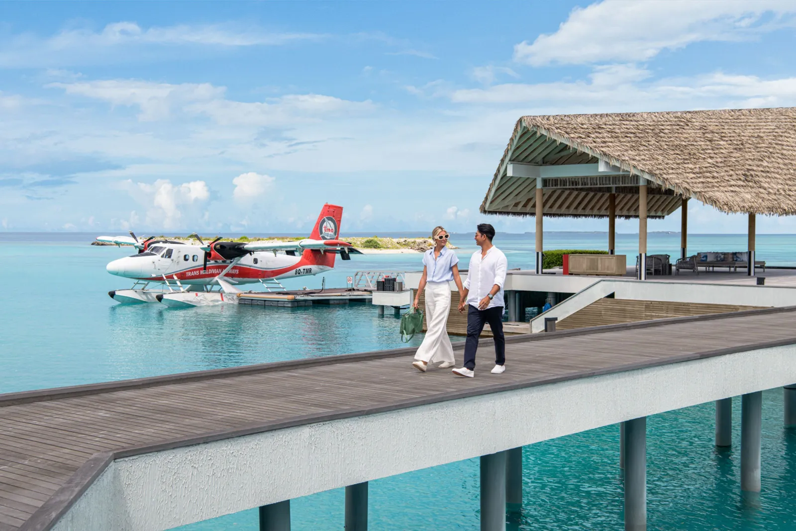 A couple on the arrival jetty, the seaplane moored at the platform and the lagoon all around